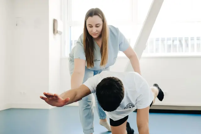 Fysioterapeutti ohjaa asiakasta liikeharjoituksessa