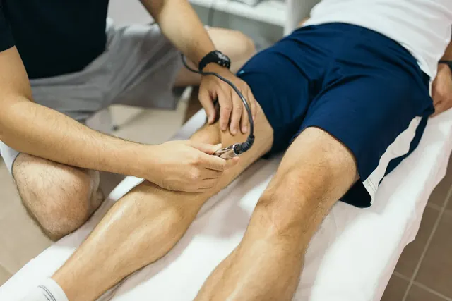 Fysioterapeutti hoitaa urheilijan polvea laserhoidolla