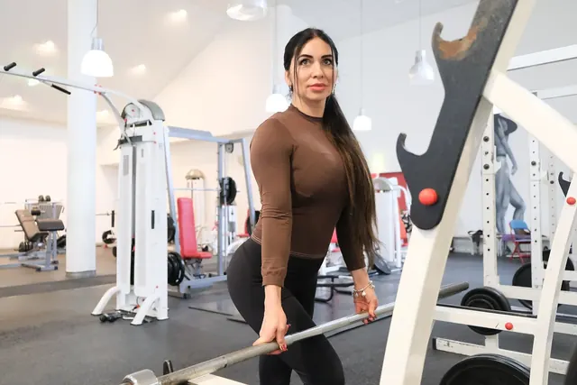 Personal trainer kuntosalilla tangon äärellä